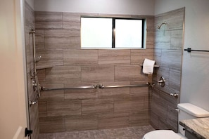 Ein Badezimmer mit Dusche, Toilette und Fenster.