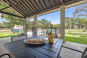 Une terrasse extérieure avec une table, des chaises et une assiette de hot-dogs.