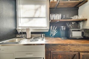 Una cocina equipada con pileta, estufa y microondas.