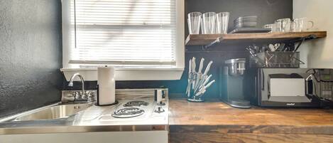 A kitchen with a sink, stove, and microwave.