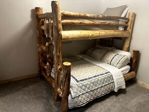 A bunk bed with a wooden frame and a quilted bedspread.