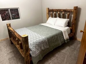 A bed with a wooden headboard, a gray bedspread, and white pillows.