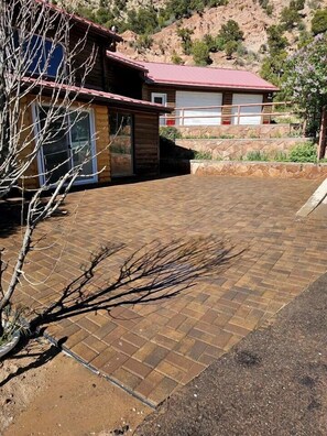Un bâtiment avec un toit rouge, une terrasse en briques et un arbre au premier plan.