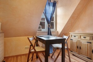A dining area with a table and chairs, a window with curtains, and a wooden cabinet.
