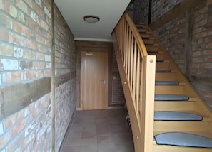Eine Treppe mit Holzbeschlägen und Geländer, die zu einer Tür führt, über der ein Schild hängt.