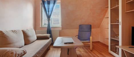 A modern room with a wooden floor, a beige sofa, a small table, a blue chair, and a wardrobe.