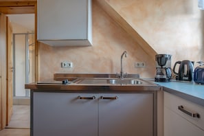 A kitchen with a stainless steel sink, a coffee maker, and a kettle on the counter. - Apartment 'Fewo Steuerboard' with Shared Terrace, Shared Garden and Wi-Fi (Röbel)