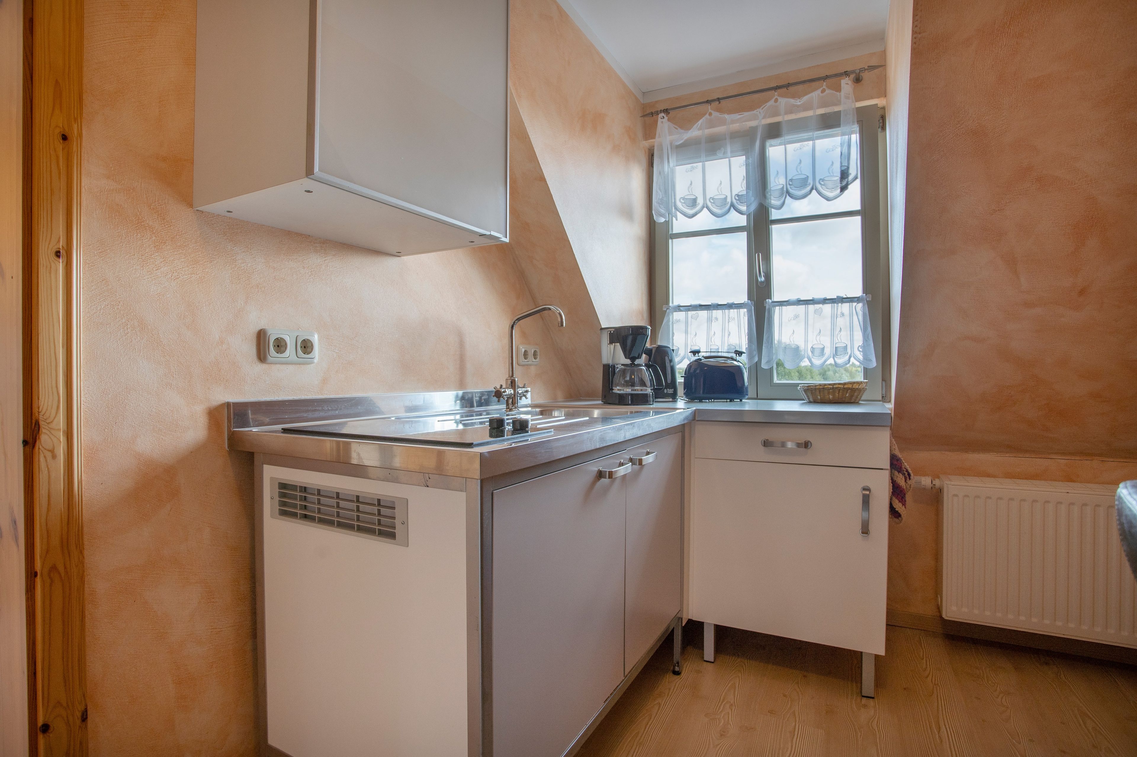 Une cuisine compacte équipée d’une cuisinière intégrée, d’un évier et d’une fenêtre donnant sur l’extérieur.