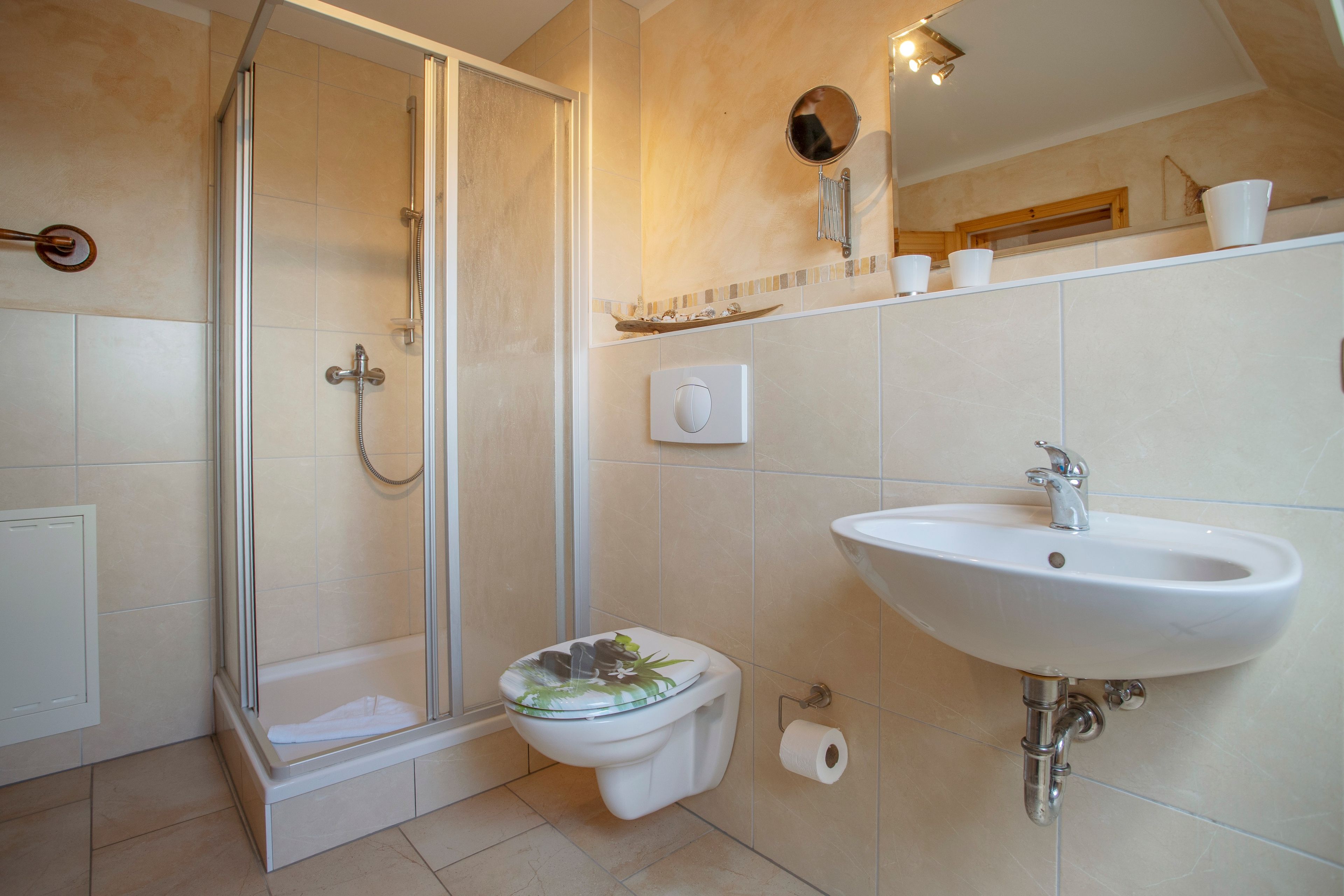 A bathroom with a shower, toilet, sink, and a mirror.
