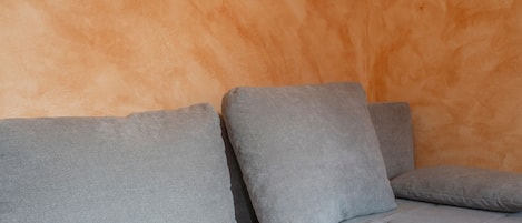 A grey sofa with a textured backrest against a wall.