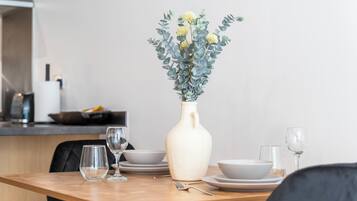 A dining table with a vase of flowers, plates, and glasses.