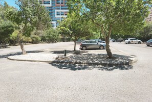 Ein Parkplatz mit Bäumen, einigen parkenden Autos und einem Gebäude im Hintergrund.