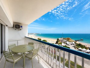 Ein Balkon mit Tisch und Stühlen, der Blick auf einen Strand und das Meer freigibt.