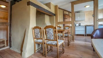 Un coin repas avec des chaises et une table en bois, une cuisine à l’arrière-plan et un plancher en bois.
