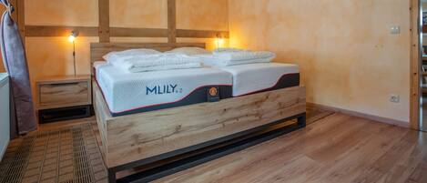 A hotel room with a wooden bed, a nightstand, and a wall-mounted lamp.