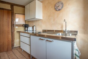 A compact kitchen with a sink, stove, and cabinets.