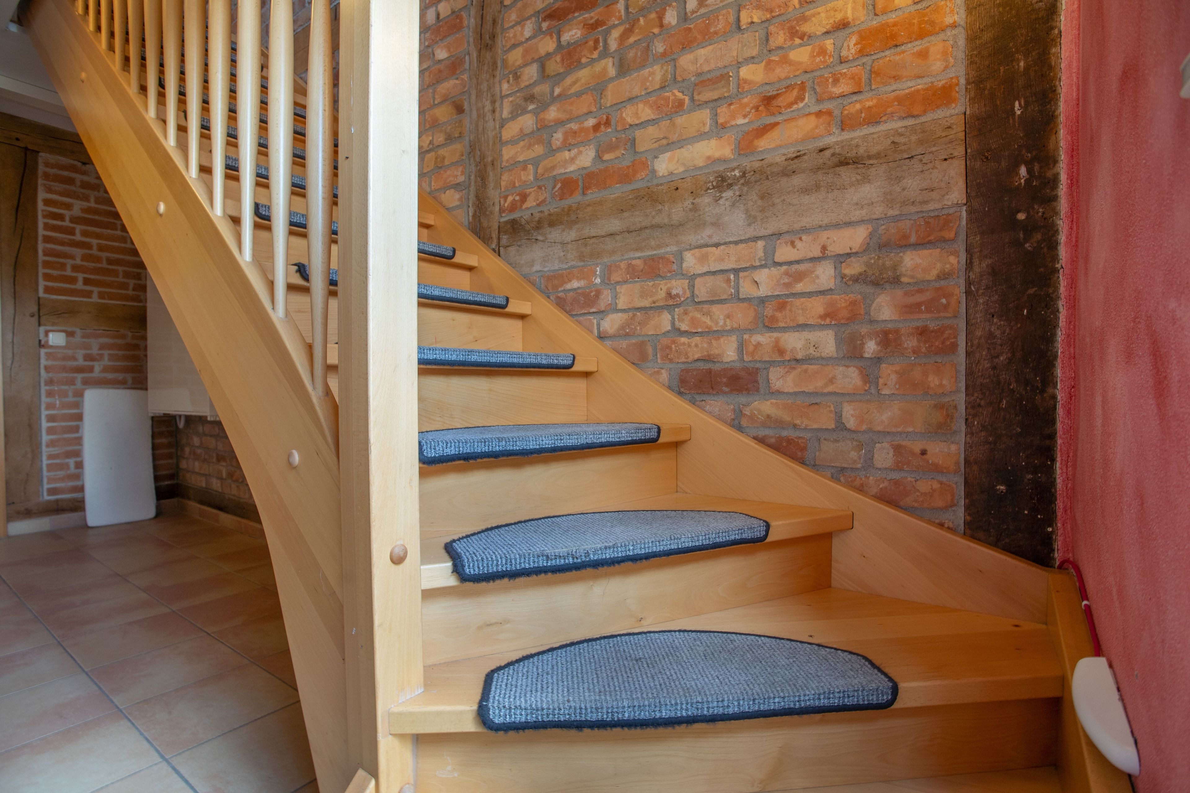 Eine Holztreppe mit blau bepflasterten Stufen und einer Ziegelwand.