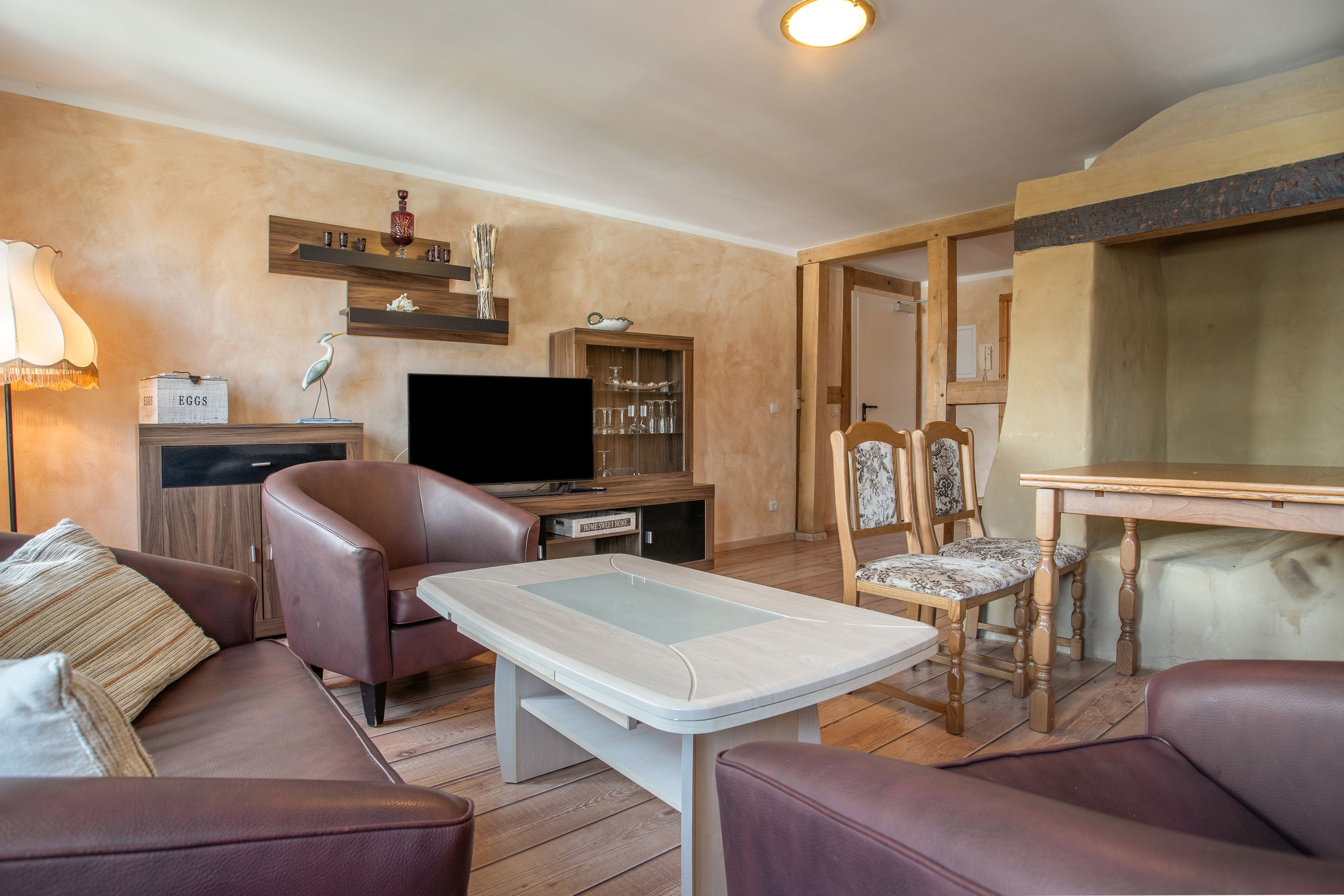 Ein Wohnzimmer mit einer Couch, einem Fernseher, einem Couchtisch und einem Essbereich mit Stühlen.