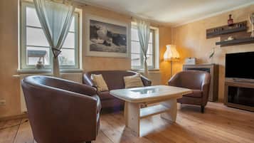 Una sala de estar con sofá, dos sillones, una mesa de centro, chimenea y televisor.