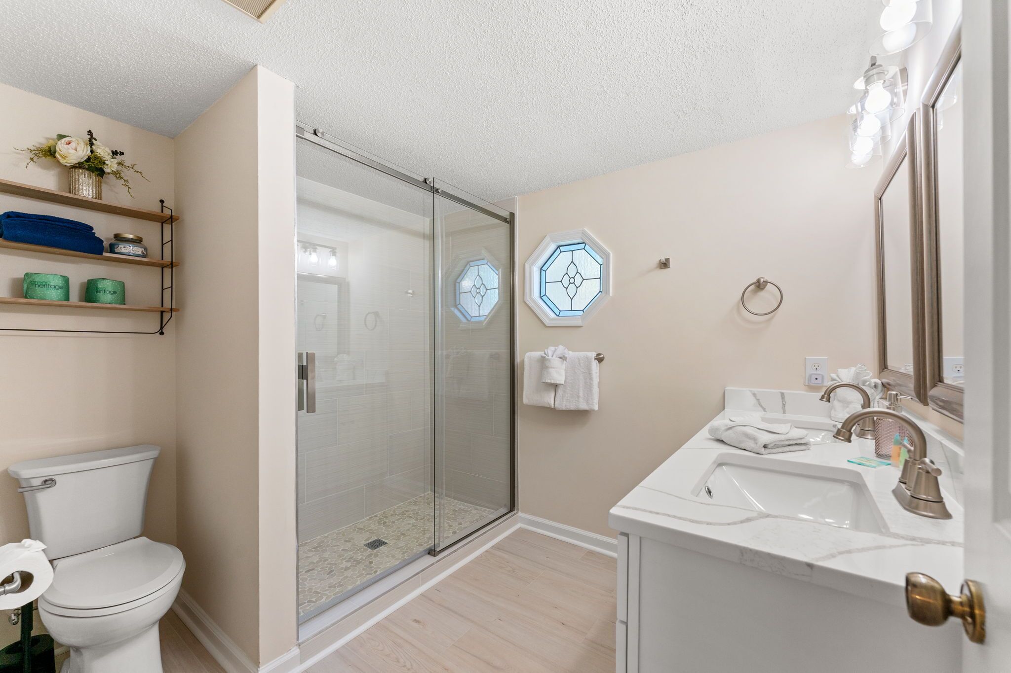 A bathroom with a toilet, shower, sink, and vanity.