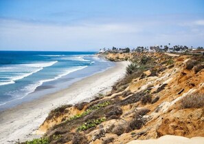 A coastal landscape with a beach, cliffs, and a distant town. - Vista Studio Oasis | Patio, Beaches & Local Dining (Vista)