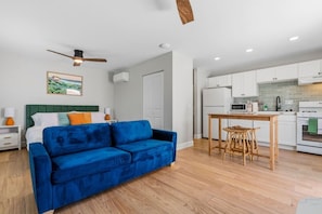 Eine moderne Wohnung mit einem blauen Sofa, einem Essbereich und einer Küchenzeile.