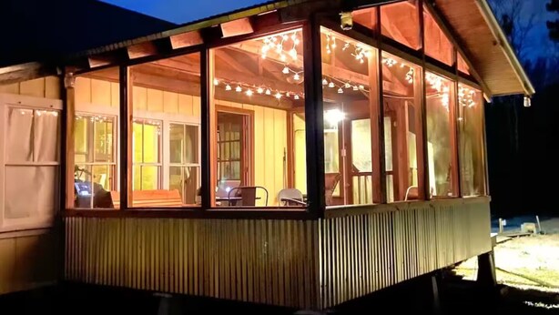 A wooden structure with large windows and string lights, likely a covered outdoor area or porch.