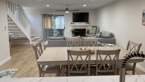 Ein modernes Wohnzimmer mit Essbereich, Kamin, Flachbildfernseher und Treppe.