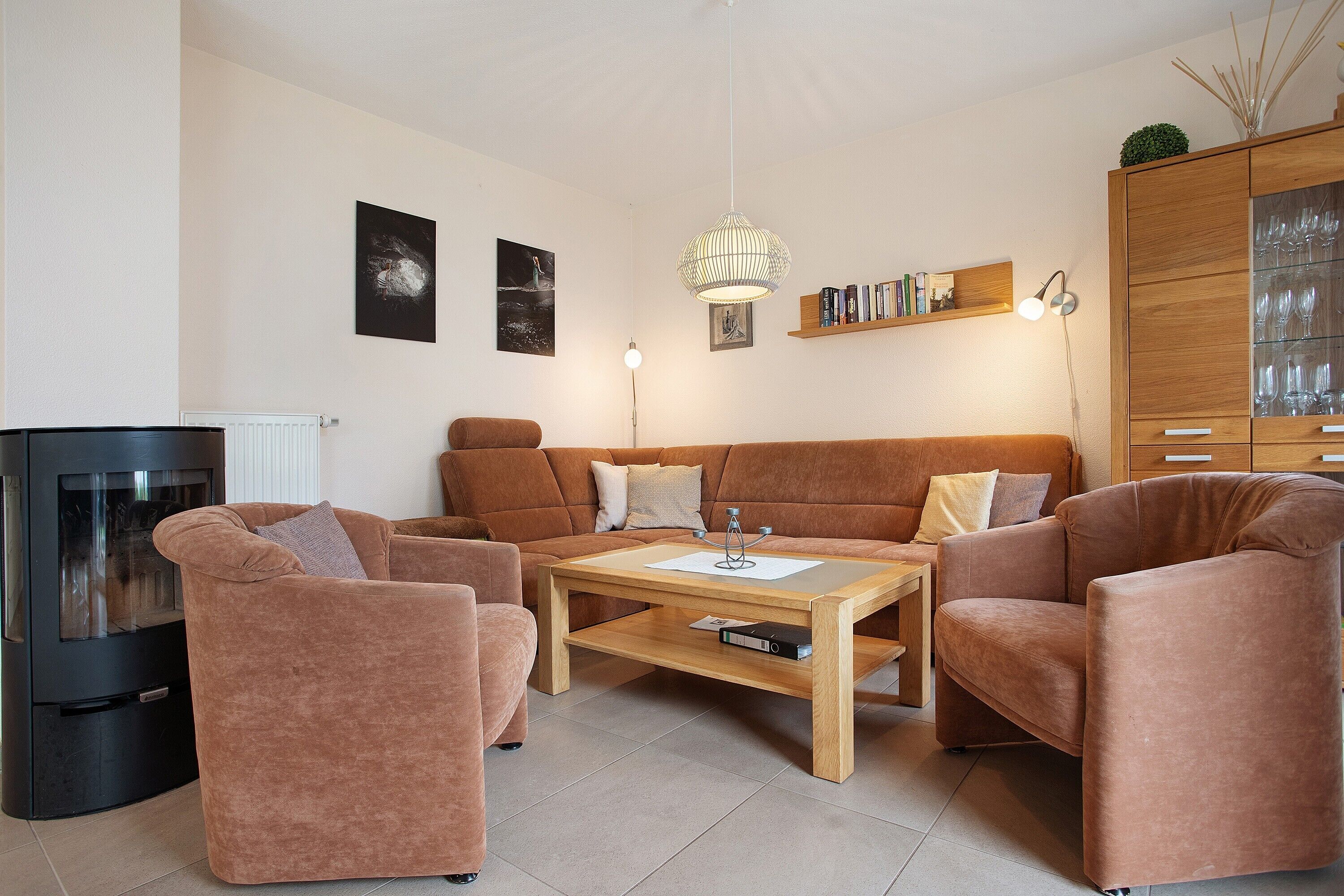 A living room with a sofa set, a coffee table, a fireplace, wall-mounted lamps, and a bookshelf.