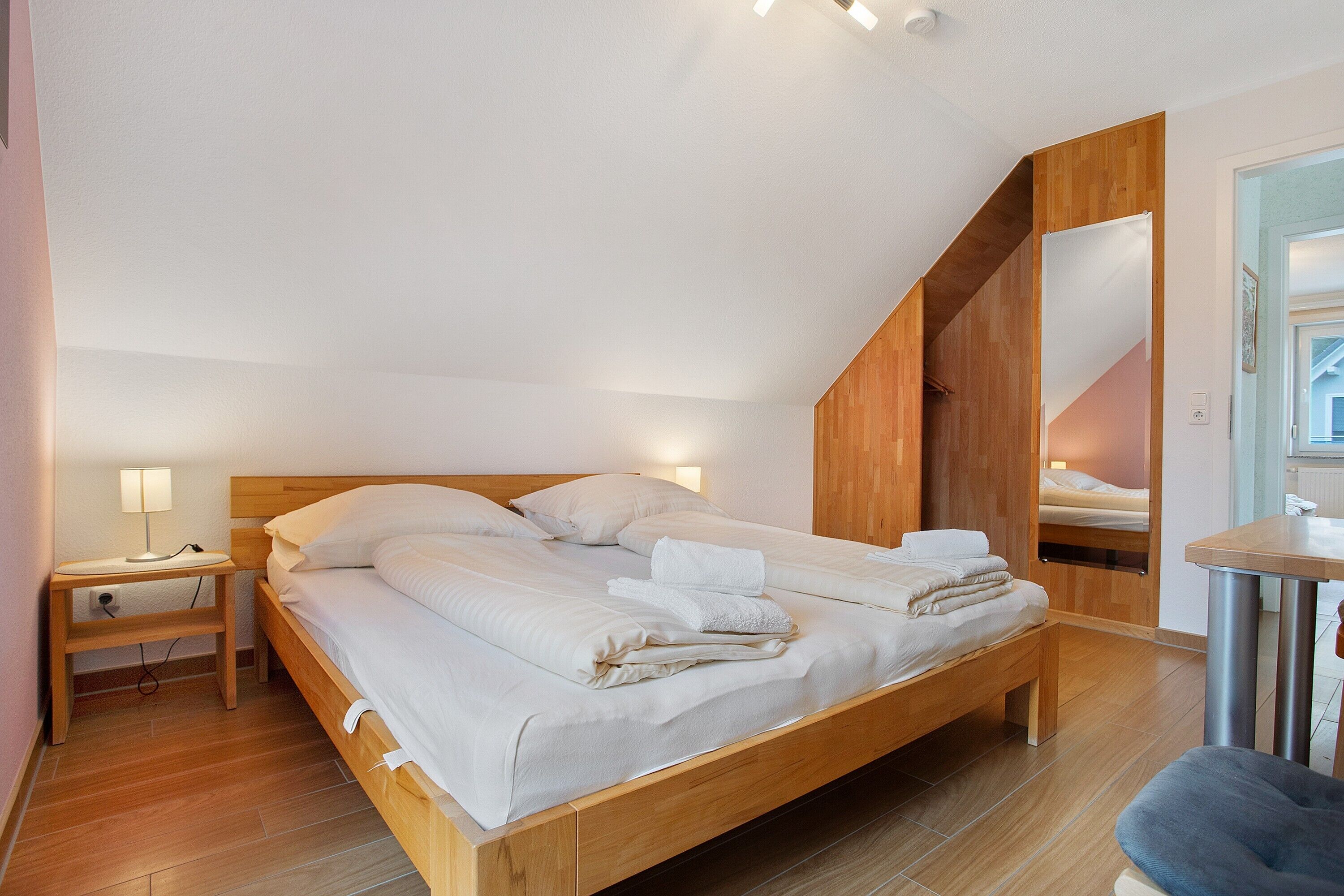 Un dormitorio con una cama de madera, una mesita de noche, un espejo y una pequeña mesa.