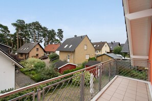 Bairro residencial com casas, uma garagem vermelha e uma cerca de metal.