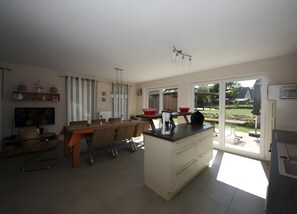 Eine moderne Küche mit Essbereich, großen Fenstern und Blick ins Freie.