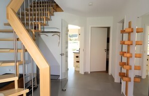 Ein modernes Interieur mit einer Holztreppe, einer Glastür, die auf einen Balkon führt, und einer Holzwandregal-Konstruktion.