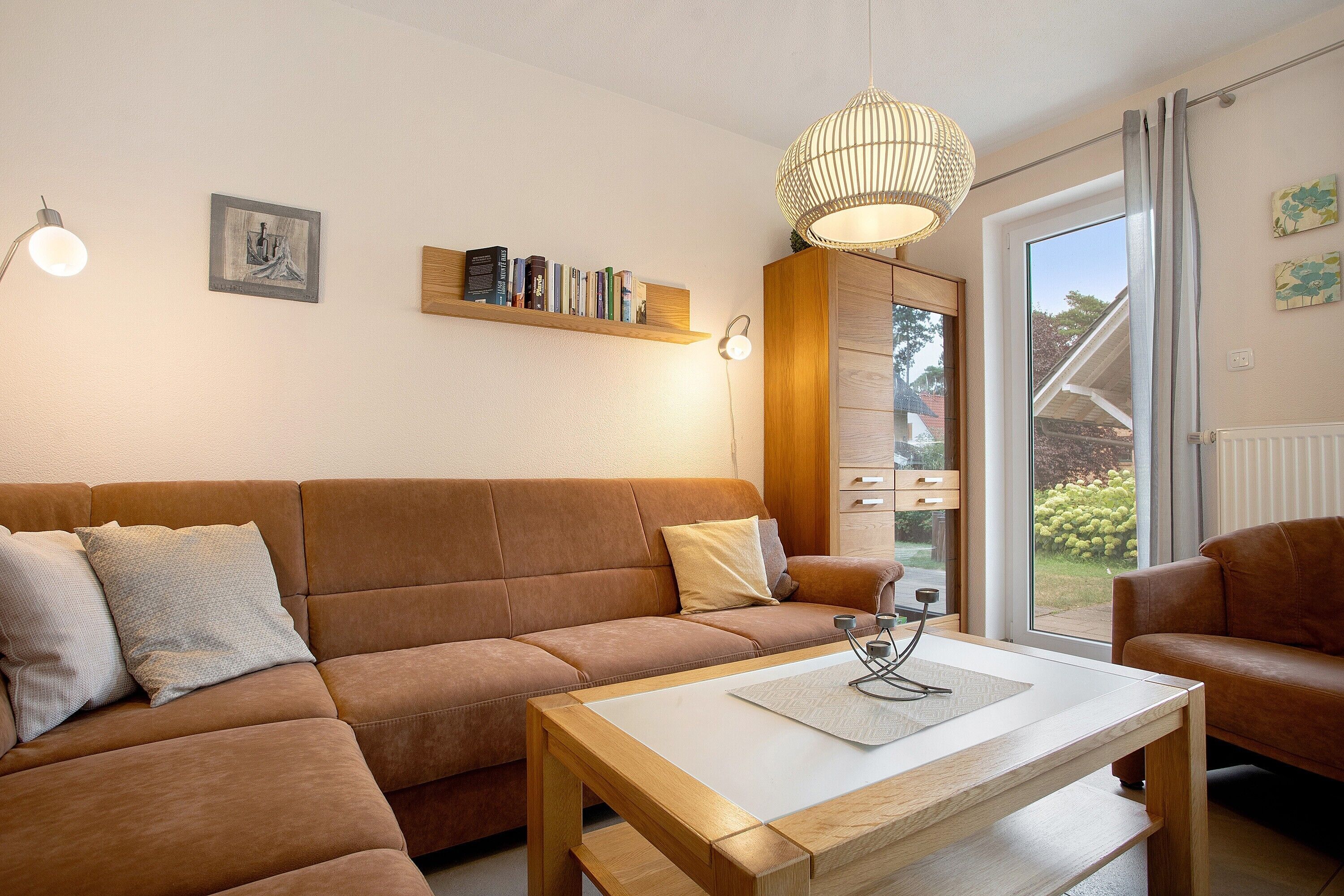 Een gezellige woonkamer met een bruine bank, een houten salontafel en een boekenkast.