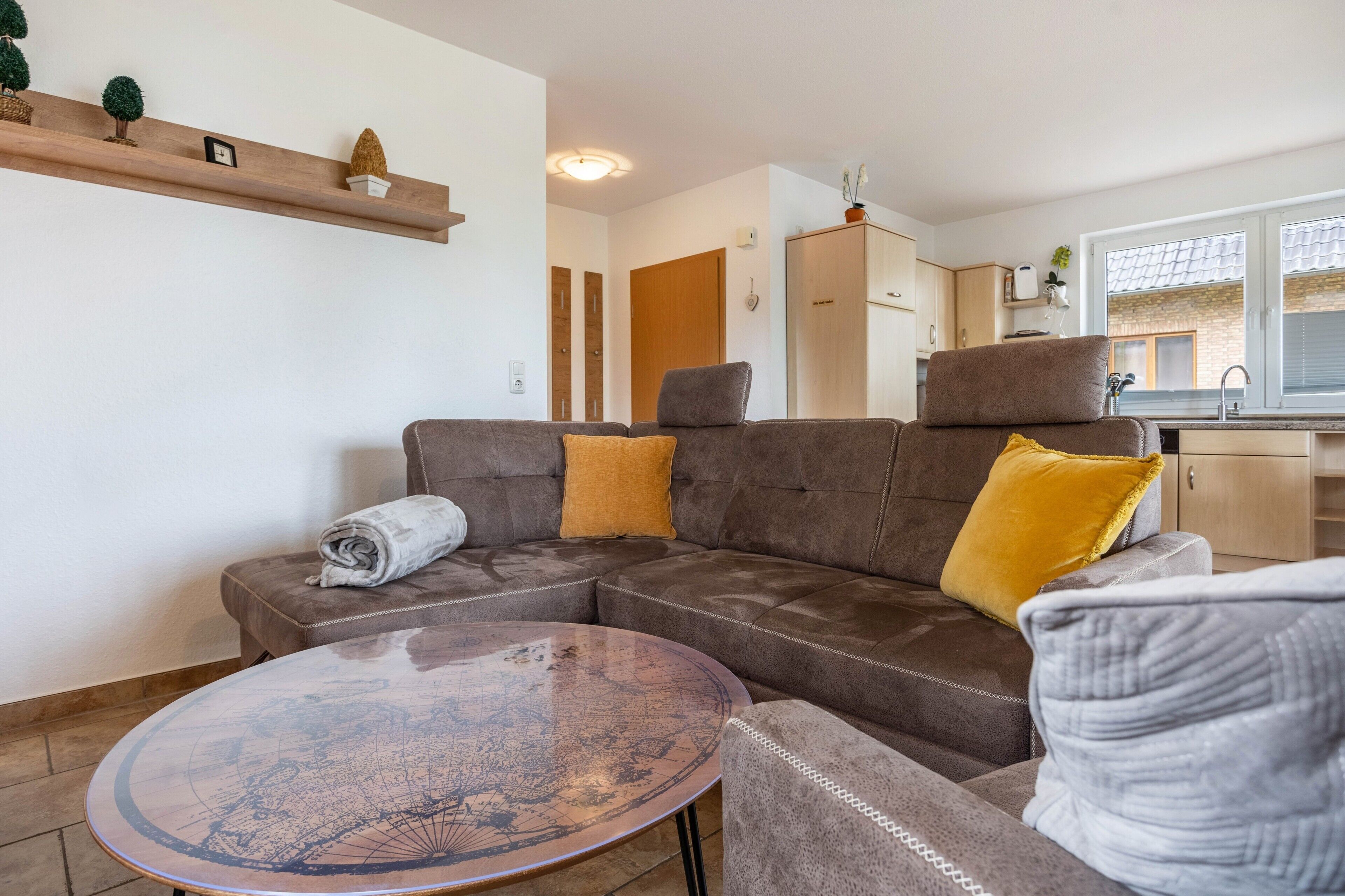 Ein Wohnzimmer mit einem braunen Sofa, einem runden Couchtisch und einem kleinen Tisch mit einer Karte.