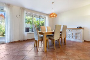Ein Essbereich mit Holztisch und -stühlen, einer Pendelleuchte und Blick auf Grünflächen.