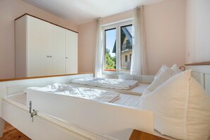 A bedroom with a bed, a wardrobe, and a window with a view of a building.