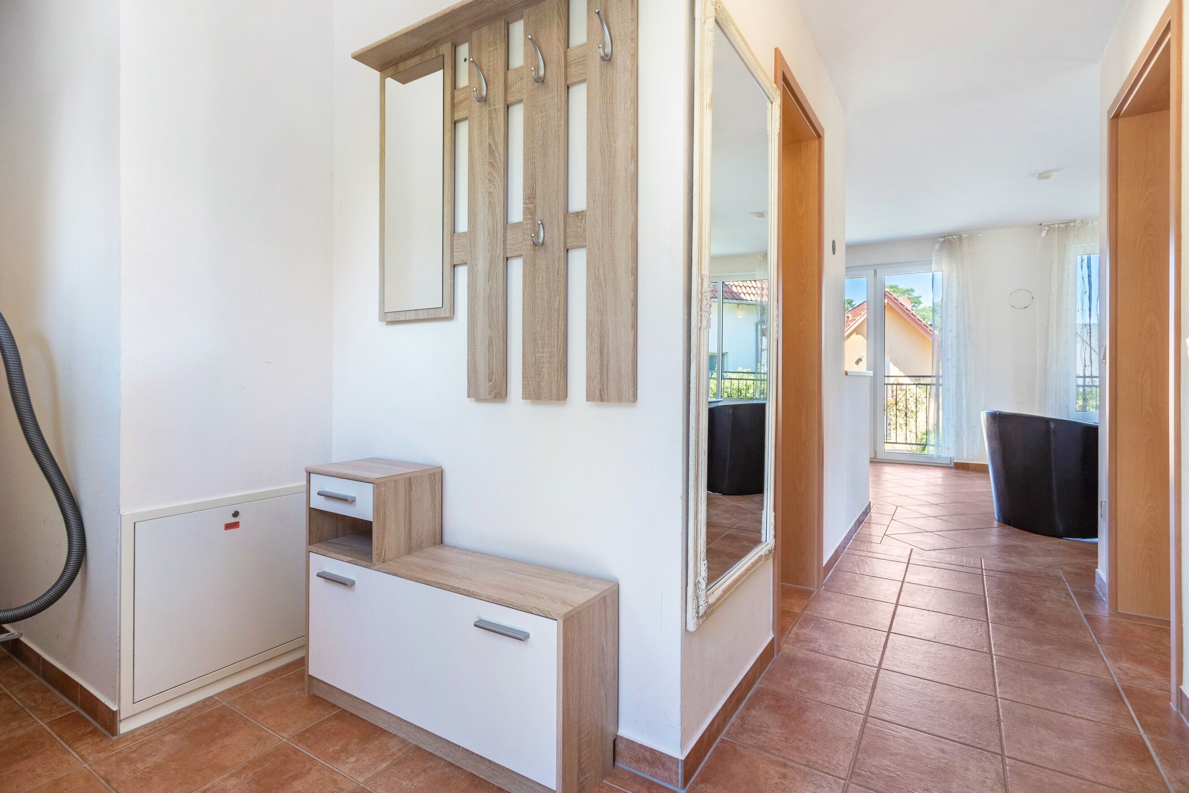 Un interior limpio y moderno con un armario de madera, un espejo y vistas a un balcón.