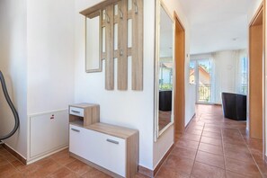 Ein sauberes, modernes Interieur mit einem Holzschrank, einem Spiegel und Blick auf einen Balkon.