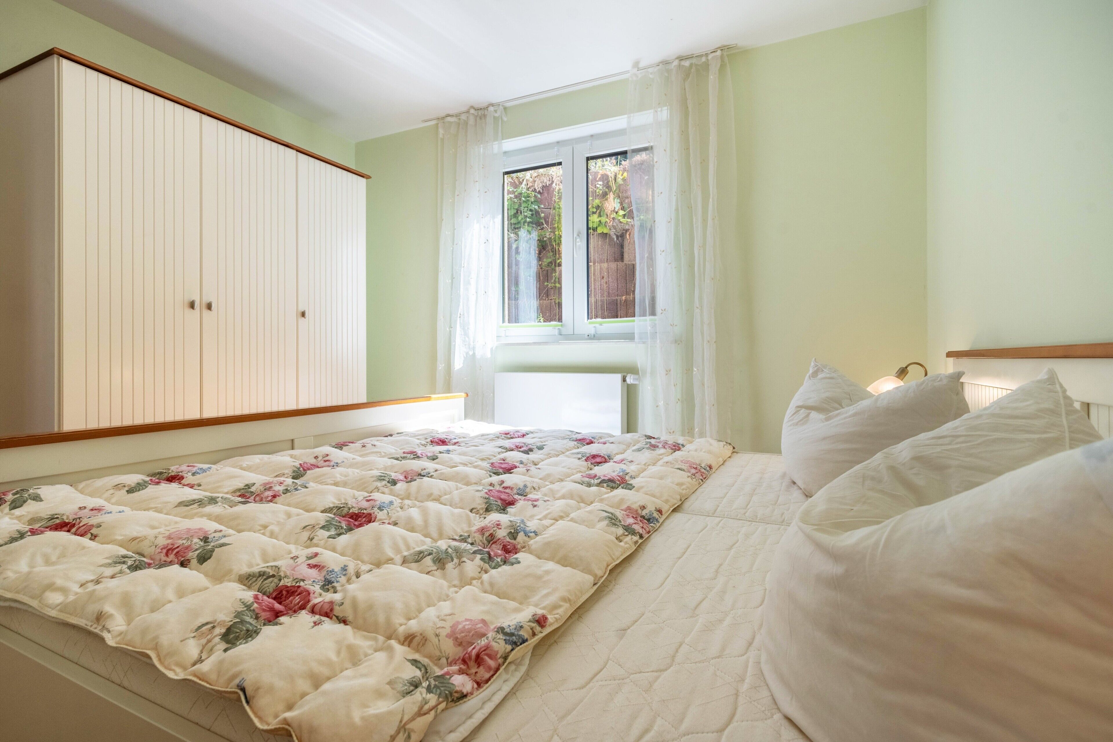 Un dormitorio con cama, armario y ventana con cortinas.