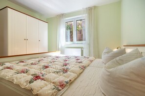 Un dormitorio con cama, armario y ventana con cortinas.