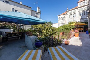An outdoor patio with a blue canopy, yellow-striped tables, and potted plants. - Coimbra Old Town Gem Family Studios, Suites with Private Bathrooms (Coimbra)