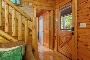 A wooden staircase leading to a room with a door and a window. - Log Cabin near Pigeon Forge | Hot Tub, Fireplace (Sevierville)
