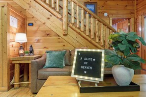 Een houten interieur met een trap, een bank, een tafel, een lamp en een bord met de tekst 'A SLICE OF HEAVEN'.
