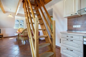 Una escalera de madera en una habitación con comedor, una ventana y una encimera de cocina.