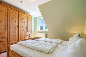 A bedroom with two beds, wooden wardrobe, and a window with a view. - Apartment '8 Og' with Private Garden and Balcony (Röbel)