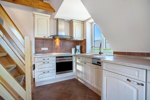 Una cocina con armarios blancos, horno empotrado y cafetera.