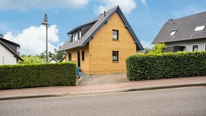 A residential house with a sloped roof, a visible chimney, and a paved driveway. - Apartment 'S 42 EG' with Private Garden and Balcony (Röbel)
