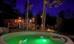 A wooden cabin with a hot tub, surrounded by trees and string lights. - Cozy Woodland Cabin Retreat – Peaceful Escape in Nature in Bethel, Maine (Bethel)