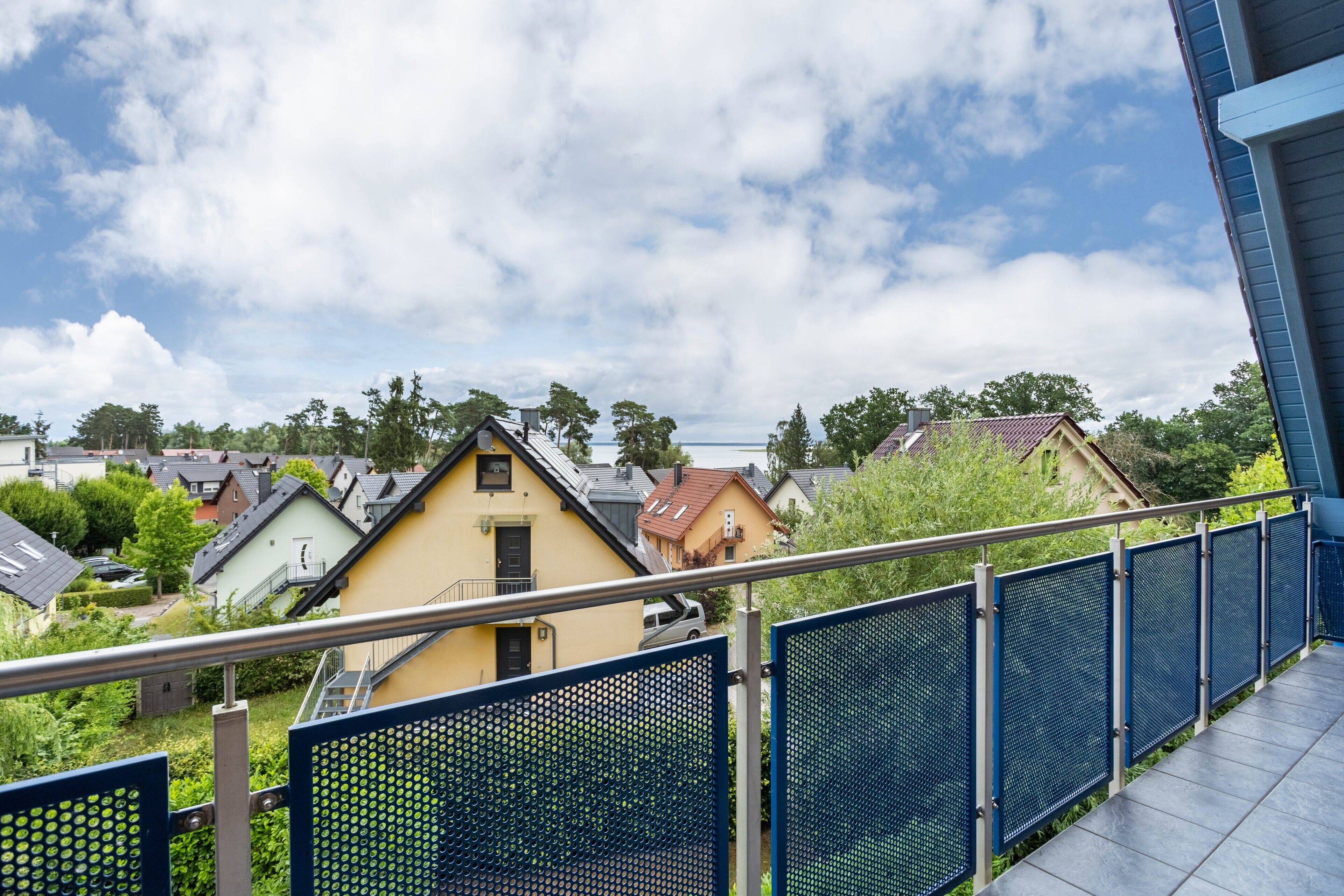 A residential area with houses, a blue metal fence, and a clear sky.